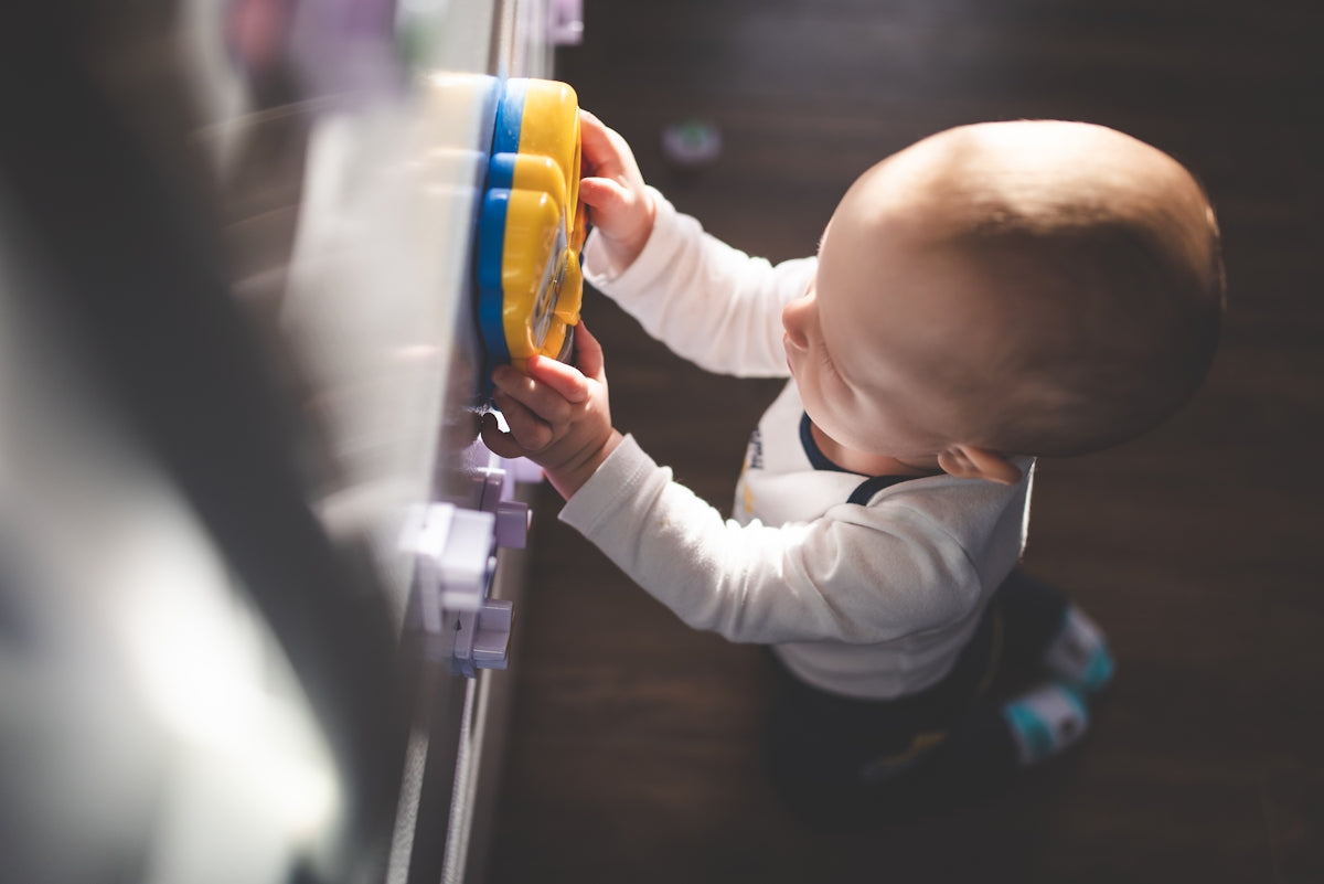 baby in white long sleeve shirt holding orange and gray toy gun