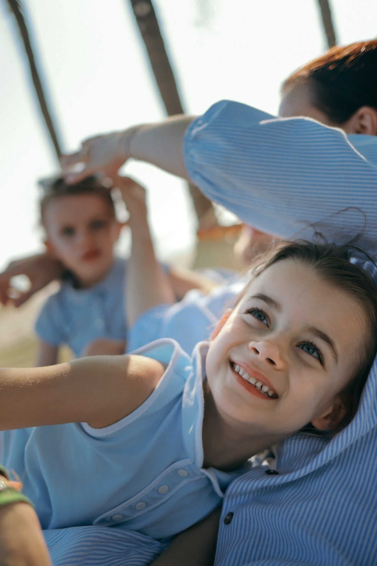 A smiling girl in her mother's arms outdoors
