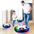 One boy and one man playing with a led soccer ball inside a room